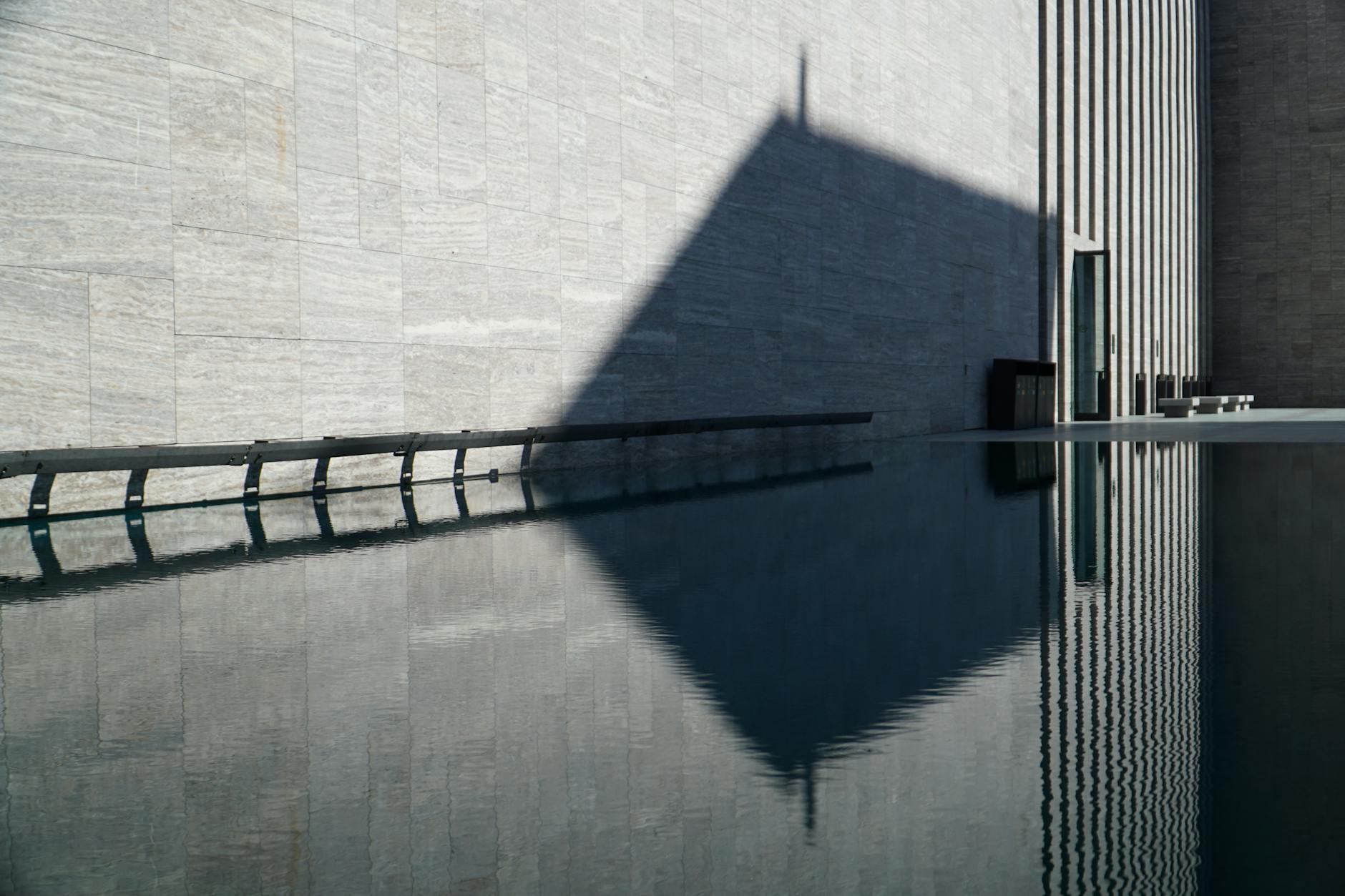 アタテュルク文化センターの近代的な外壁と水面に映る幾何学的な影の景観。