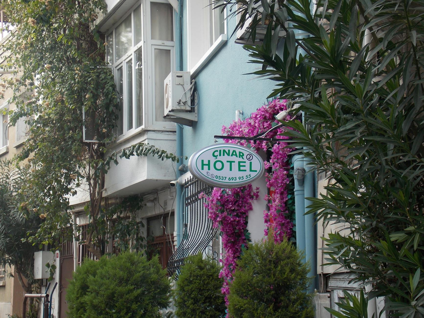 ピンクの花々に囲まれた「チナルホテル」の看板が、宿泊施設の魅力を伝えています。