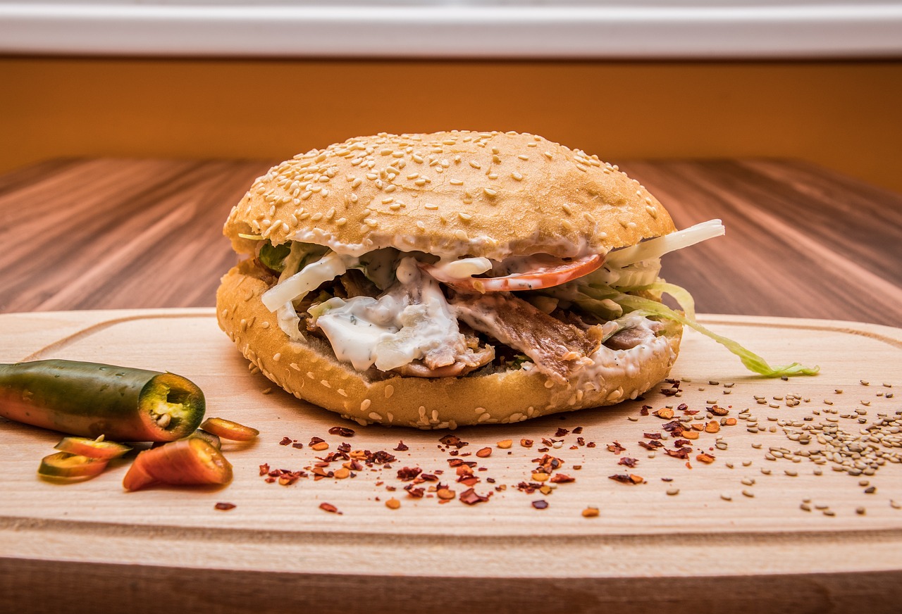 木のボードに乗せられた、ソースたっぷりで色鮮やかなドネルケバブサンド。